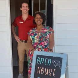 two people smiling in front of a sign