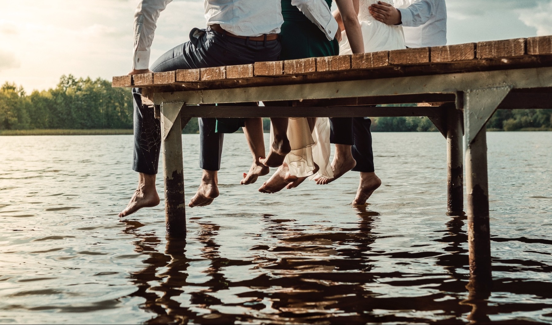 people sitting on a dock with their feet above water